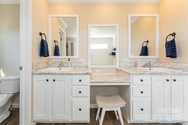 full bath with toilet, ornamental molding, two vanities, and a sink