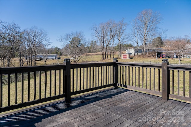 wooden deck featuring a storage shed, a yard, and an outbuilding