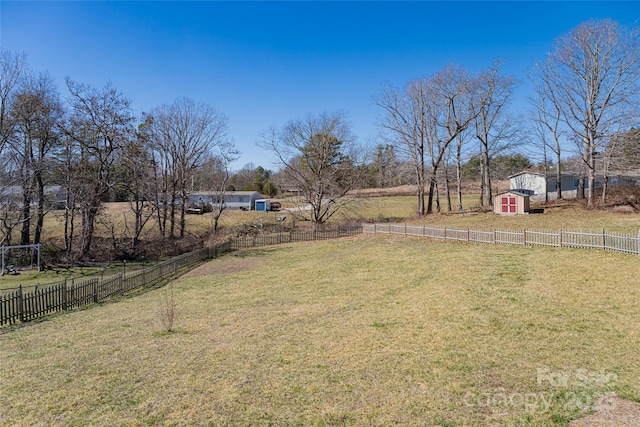 view of yard featuring a rural view, fence, an outdoor structure, and a shed