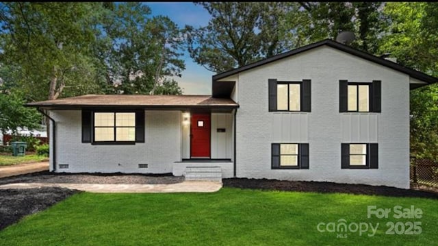 tri-level home with brick siding, fence, crawl space, board and batten siding, and a front yard