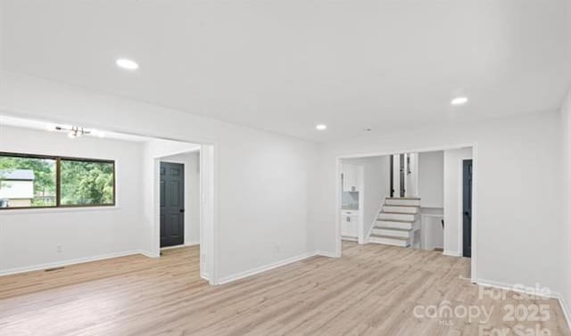 spare room with stairs, light wood-type flooring, baseboards, and recessed lighting