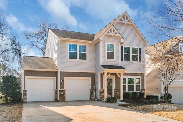 craftsman inspired home with an attached garage, concrete driveway, a shingled roof, and stone siding