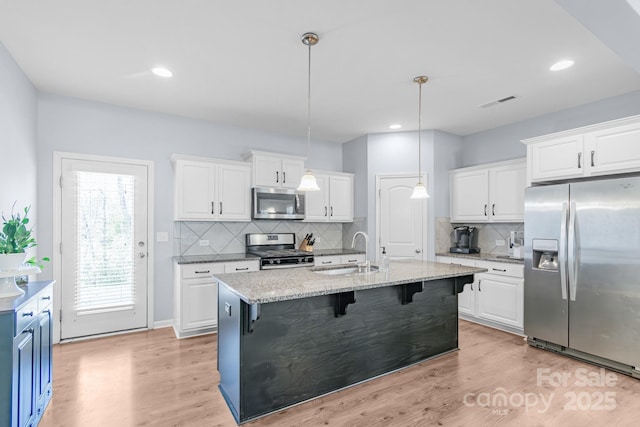 kitchen with appliances with stainless steel finishes, a breakfast bar, white cabinetry, and a sink