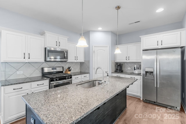 kitchen featuring appliances with stainless steel finishes, white cabinets, a sink, and visible vents