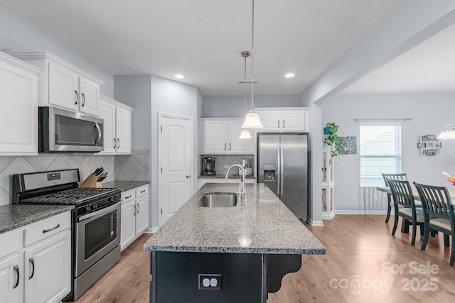 kitchen with light wood finished floors, white cabinetry, stainless steel appliances, and a sink