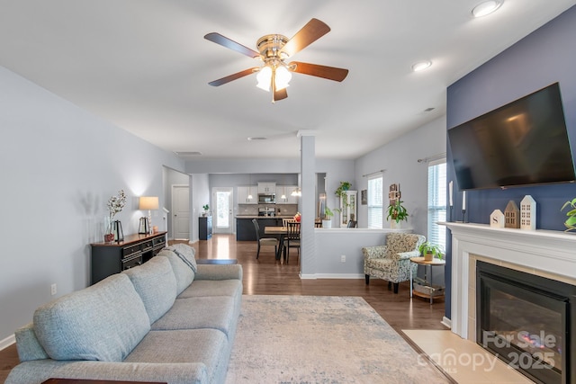 living area featuring recessed lighting, plenty of natural light, wood finished floors, and a fireplace with flush hearth