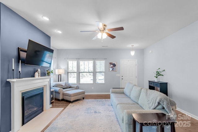 living room with baseboards, a fireplace with flush hearth, ceiling fan, wood finished floors, and recessed lighting