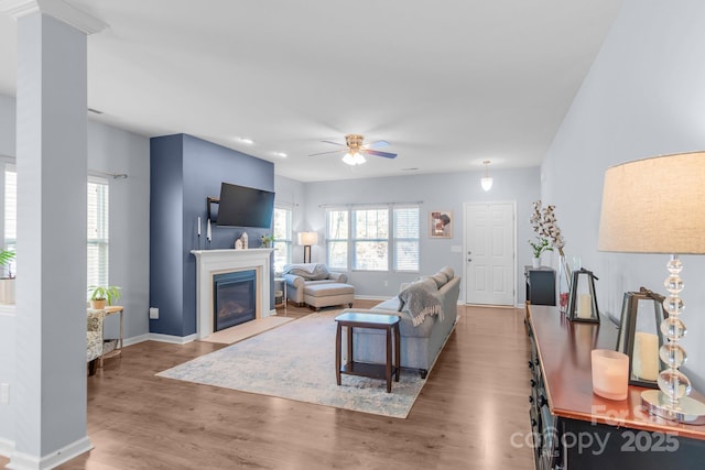 living area featuring a wealth of natural light, a fireplace with flush hearth, baseboards, and wood finished floors