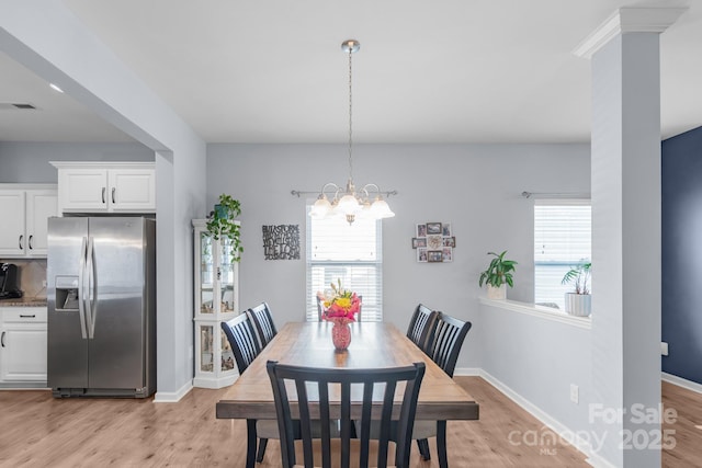 dining area featuring a chandelier, light wood finished floors, visible vents, and baseboards