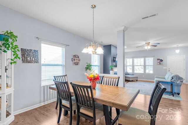 dining area with light wood finished floors, baseboards, visible vents, and ceiling fan with notable chandelier