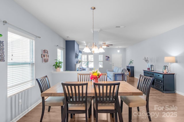 dining area with light wood finished floors, visible vents, baseboards, and a notable chandelier