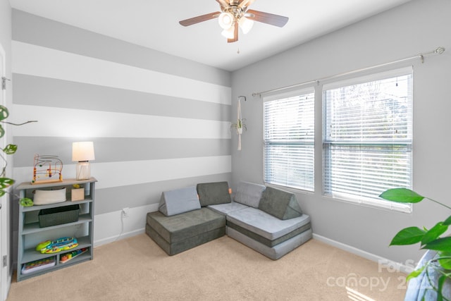 living area with carpet flooring, a ceiling fan, and baseboards