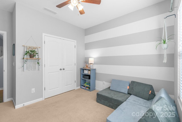 living area featuring carpet floors, baseboards, visible vents, and a ceiling fan