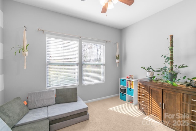 sitting room featuring carpet floors, baseboards, and a ceiling fan