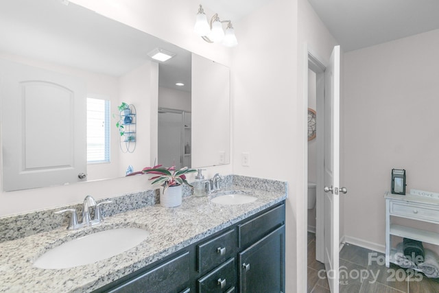 bathroom with double vanity, tile patterned flooring, a sink, and baseboards