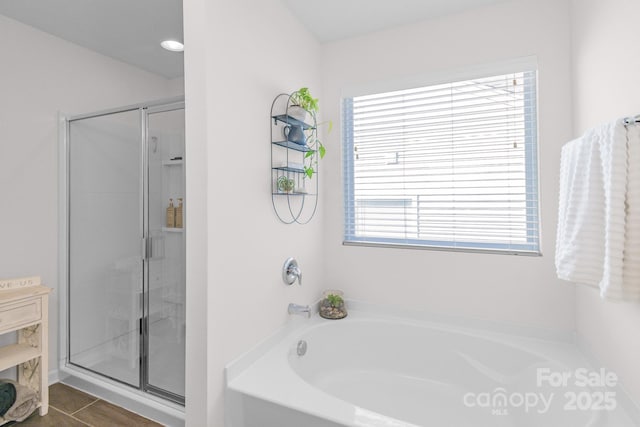 bathroom featuring a stall shower and a bath