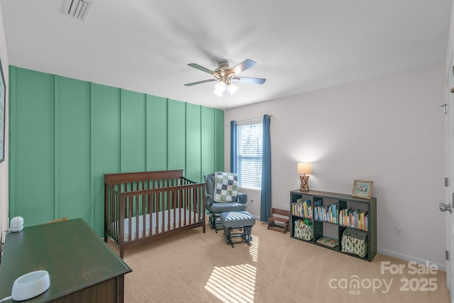 bedroom featuring a ceiling fan, visible vents, a crib, and carpet flooring