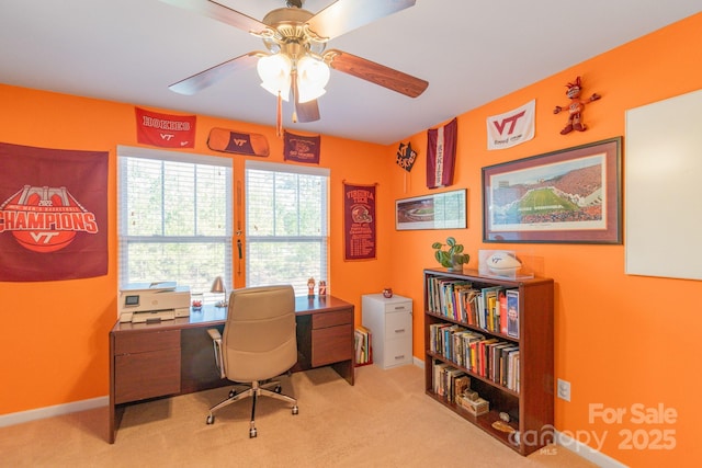 carpeted office space with ceiling fan and baseboards