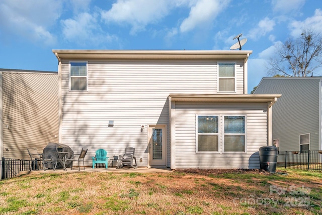 rear view of house featuring a patio area, fence, and a lawn