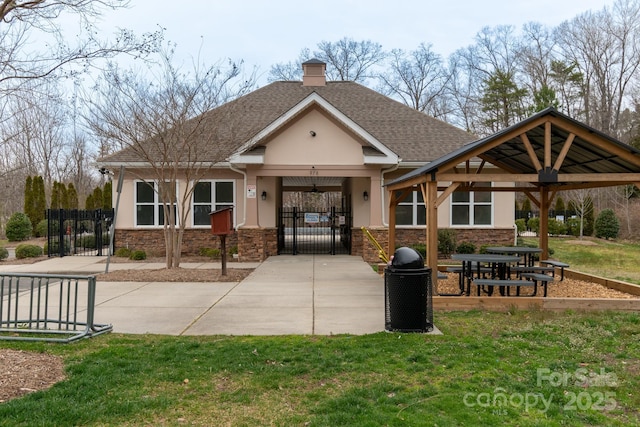 view of front facade with a shingled roof, a gazebo, stone siding, a gate, and stucco siding