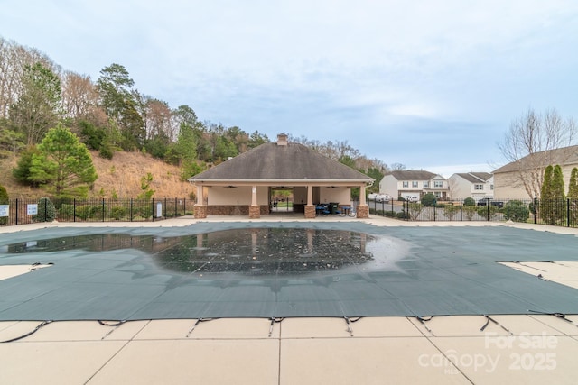 community pool with a patio area and fence