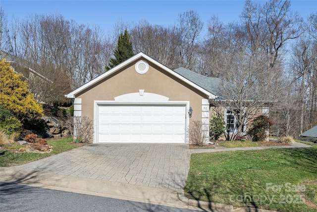 ranch-style home featuring a front lawn, decorative driveway, an attached garage, and stucco siding