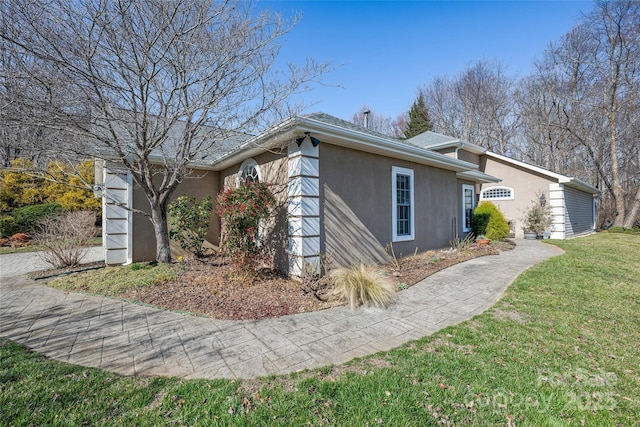 view of side of property with a lawn and stucco siding