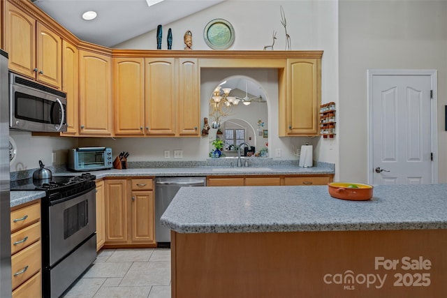 kitchen with a toaster, lofted ceiling, appliances with stainless steel finishes, light stone counters, and a sink