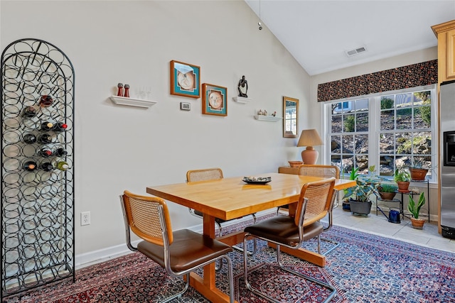 dining area featuring high vaulted ceiling, light tile patterned flooring, visible vents, and baseboards