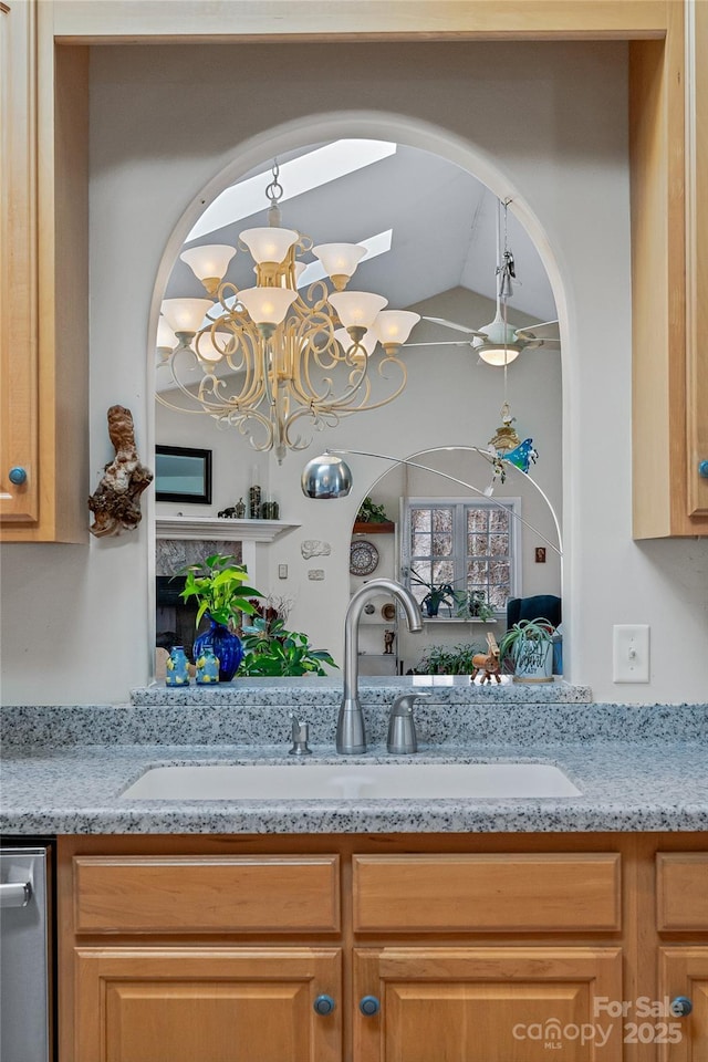 kitchen with a chandelier, stainless steel dishwasher, a sink, and light stone countertops