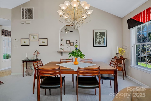 dining room featuring lofted ceiling, baseboards, light carpet, and arched walkways