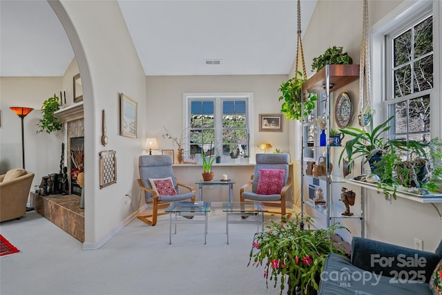 sitting room with visible vents, arched walkways, baseboards, a tile fireplace, and carpet