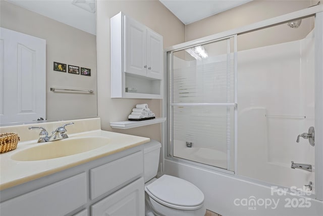 bathroom featuring toilet, shower / bath combination with glass door, and vanity