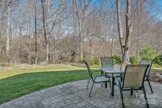 view of patio / terrace with outdoor dining space and a view of trees