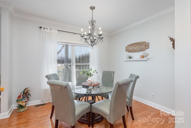 dining room featuring an inviting chandelier, crown molding, baseboards, and wood finished floors