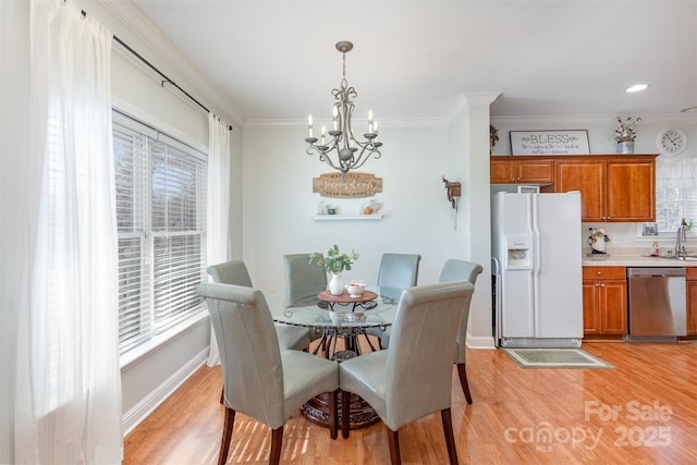 dining area featuring light wood-style floors, a notable chandelier, baseboards, and crown molding