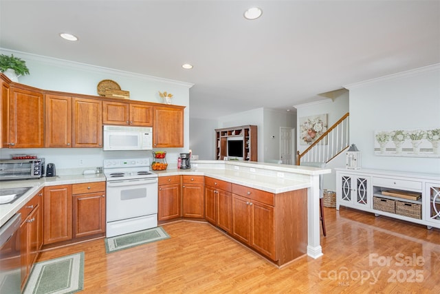 kitchen with a peninsula, white appliances, brown cabinets, and light countertops