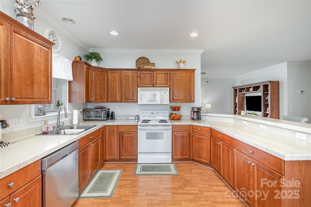 kitchen with light countertops, white appliances, a peninsula, and a sink