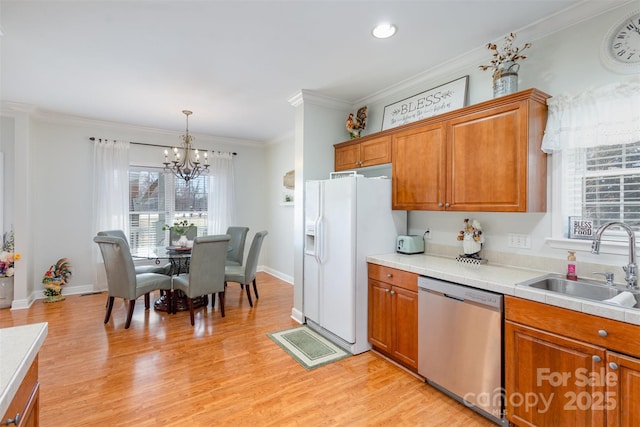 kitchen featuring a sink, stainless steel dishwasher, brown cabinets, white fridge with ice dispenser, and pendant lighting