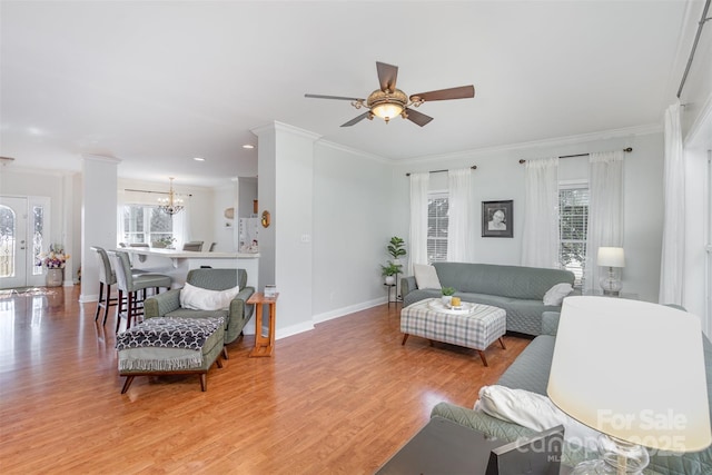 living room featuring a wealth of natural light, crown molding, baseboards, and wood finished floors