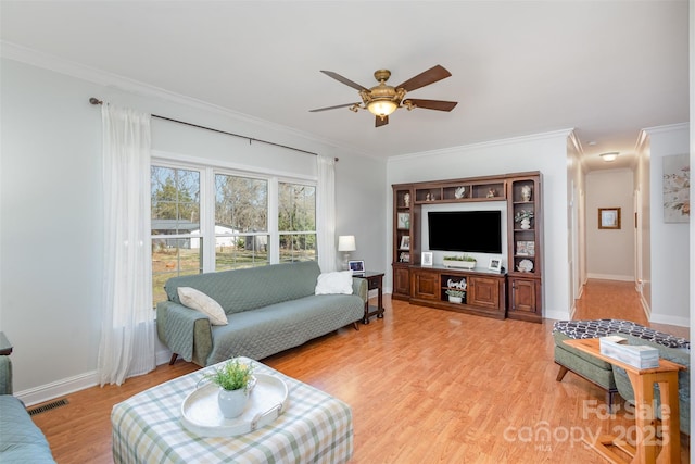 living room with light wood-style floors, baseboards, visible vents, and crown molding