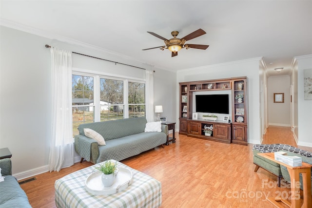 living room with ceiling fan, visible vents, baseboards, light wood-style floors, and crown molding