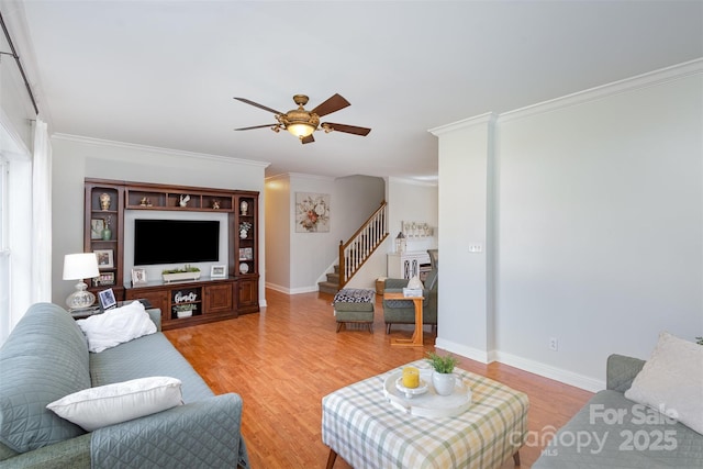 living room featuring stairs, crown molding, baseboards, and light wood-style floors