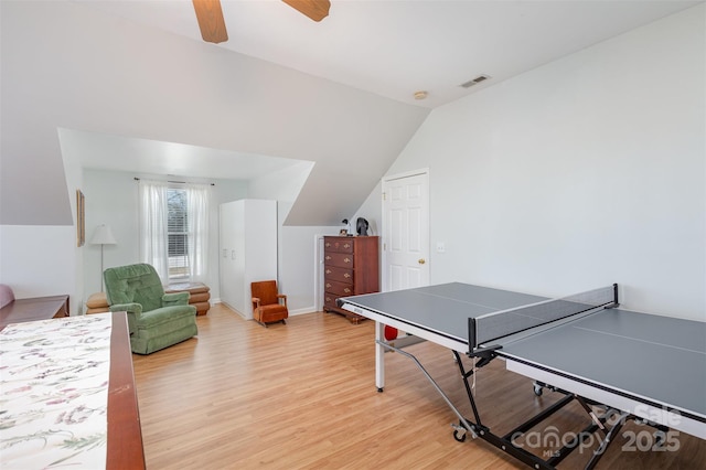 recreation room featuring baseboards, visible vents, ceiling fan, wood finished floors, and vaulted ceiling