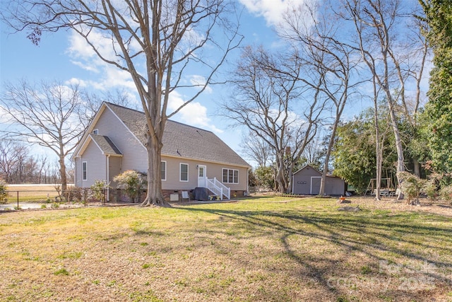 exterior space featuring roof with shingles, a lawn, and fence