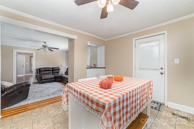 dining room with baseboards, visible vents, a textured ceiling, and ornamental molding