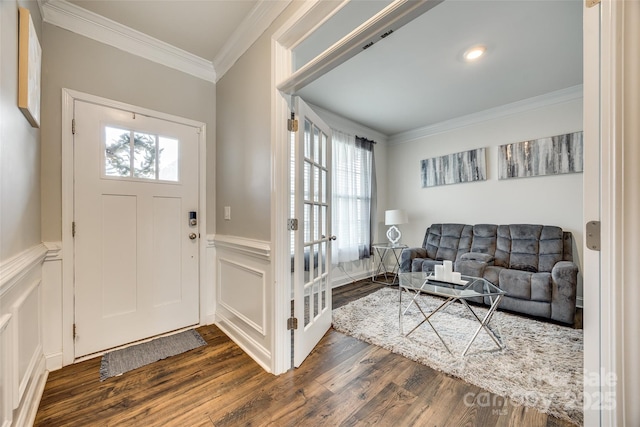 entrance foyer featuring dark wood-type flooring, a wainscoted wall, crown molding, and a decorative wall