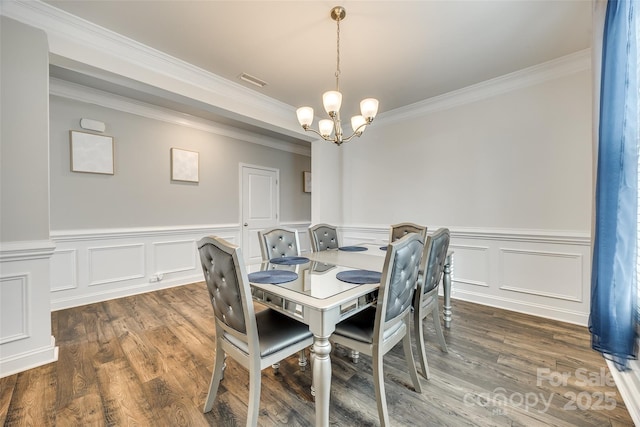 dining space featuring a chandelier, dark wood-type flooring, a wainscoted wall, and ornamental molding