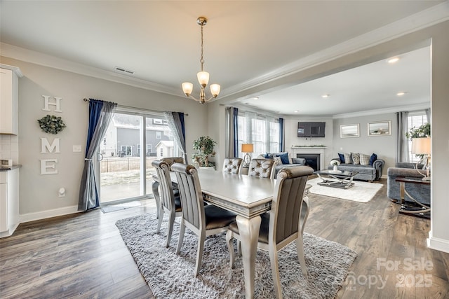 dining room featuring ornamental molding, a fireplace, wood finished floors, and visible vents