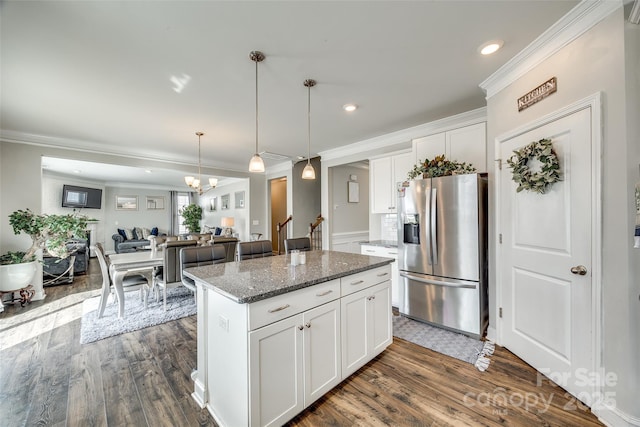 kitchen with dark stone counters, open floor plan, stainless steel fridge, and white cabinetry